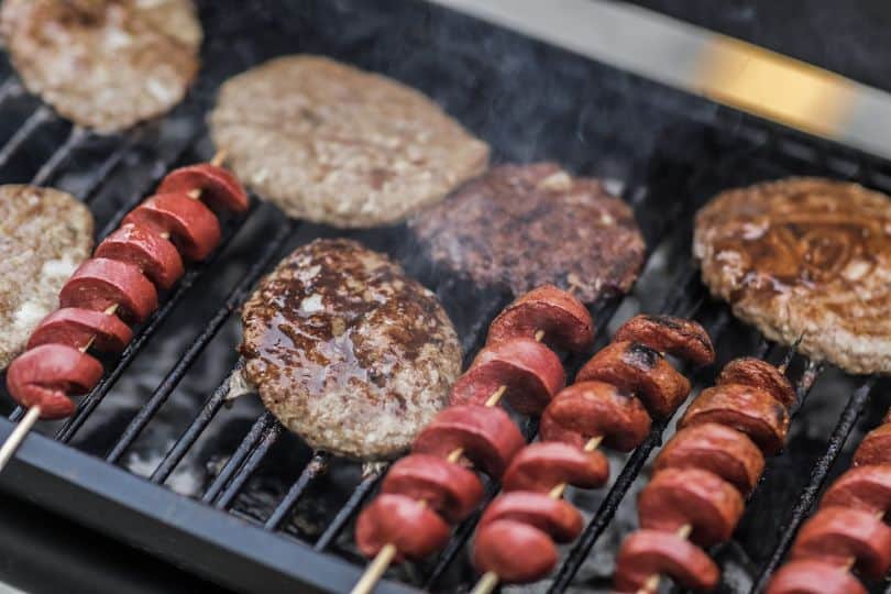 swirly sausages and burger patties on bbq grill