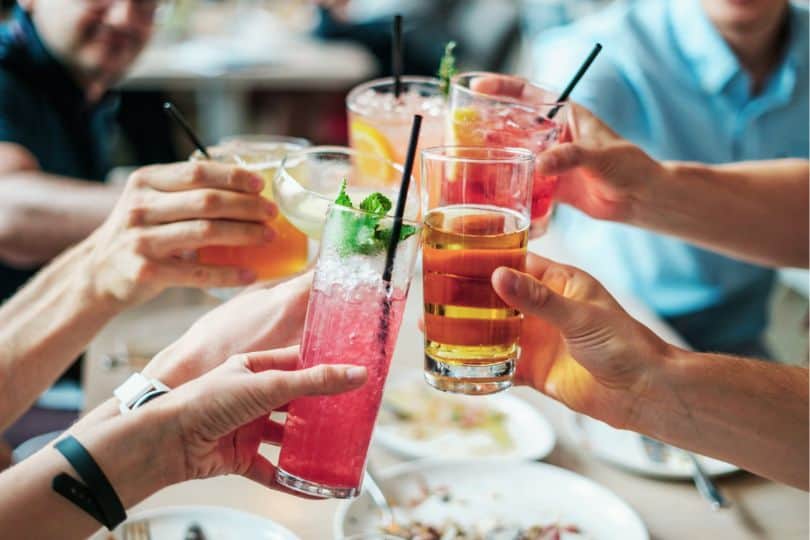 hands holding various cocktails in cheers