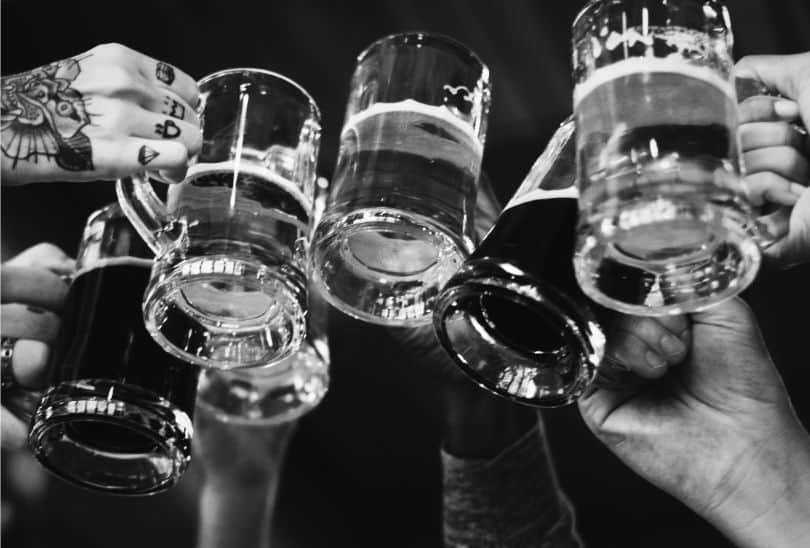 hands cheersing pint glasses of beer