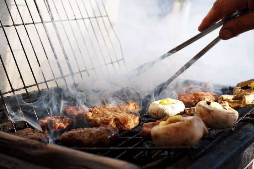 hand tending bbq food with tongs