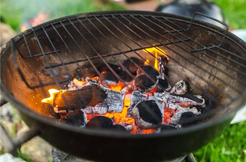 bottom half of kettle charcoal grill with fire lit