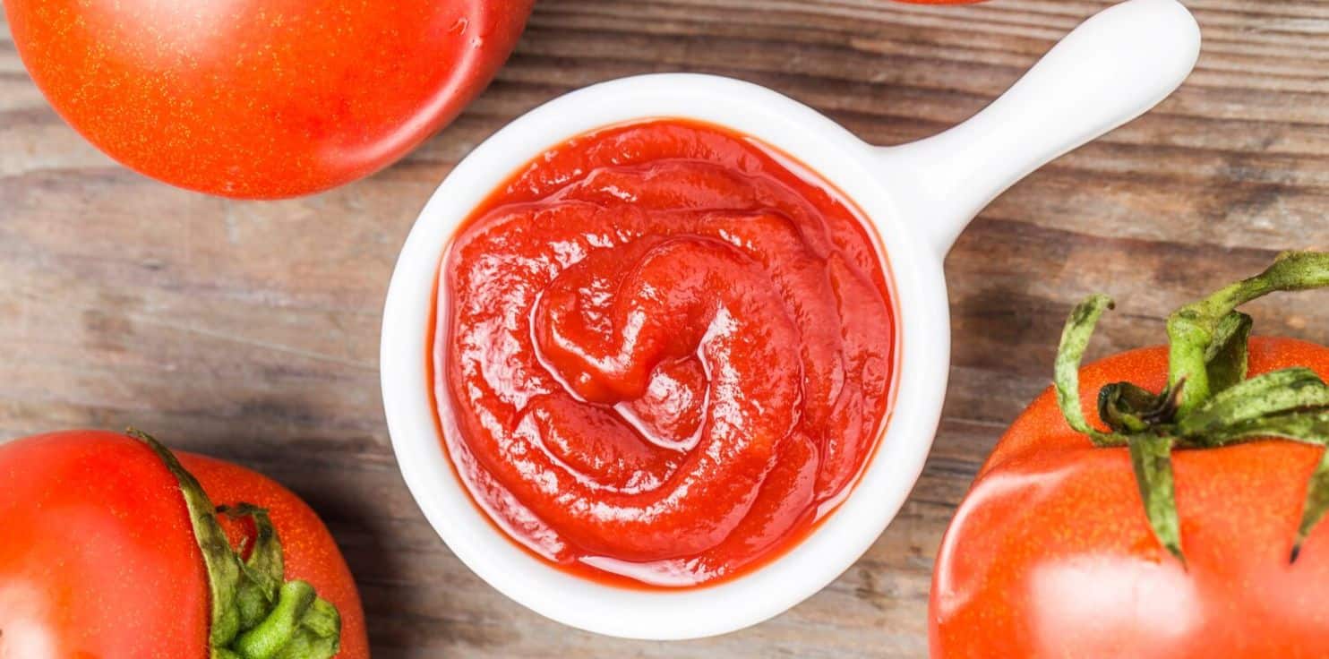 ketchup and tomato on a wooden chopping board