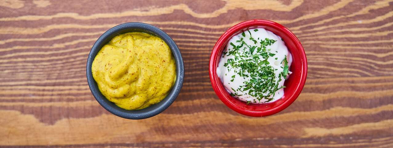 pot of mustard and mayonnaise on wooden surface