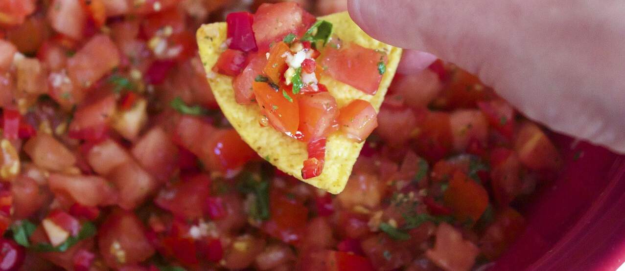 hand holding chip with pico de gallo