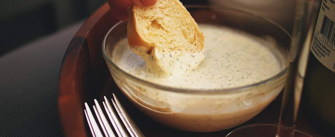 bread dipping in ranch dressing in glass bowl