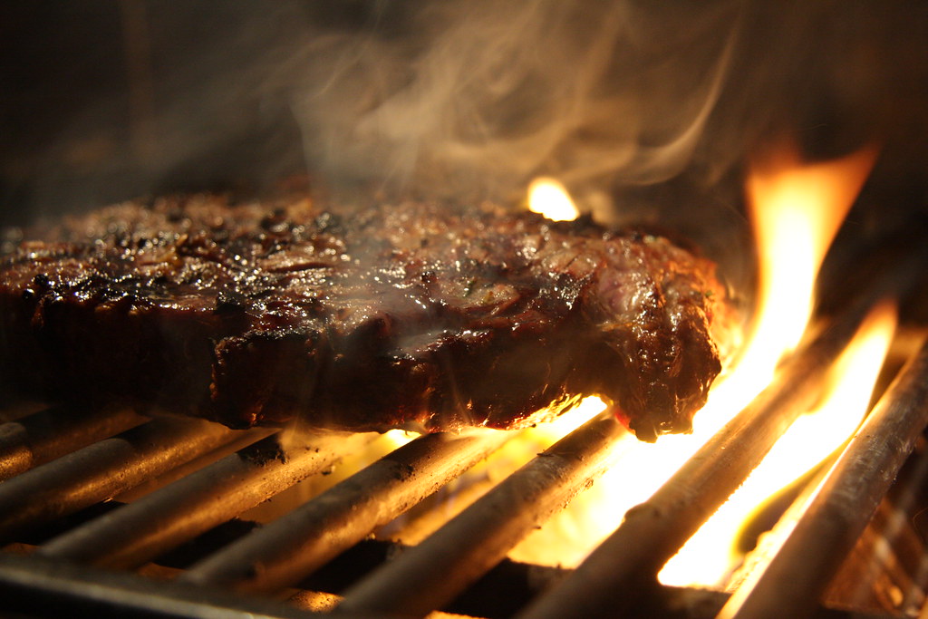 Steak cooking on an open-flame grill.