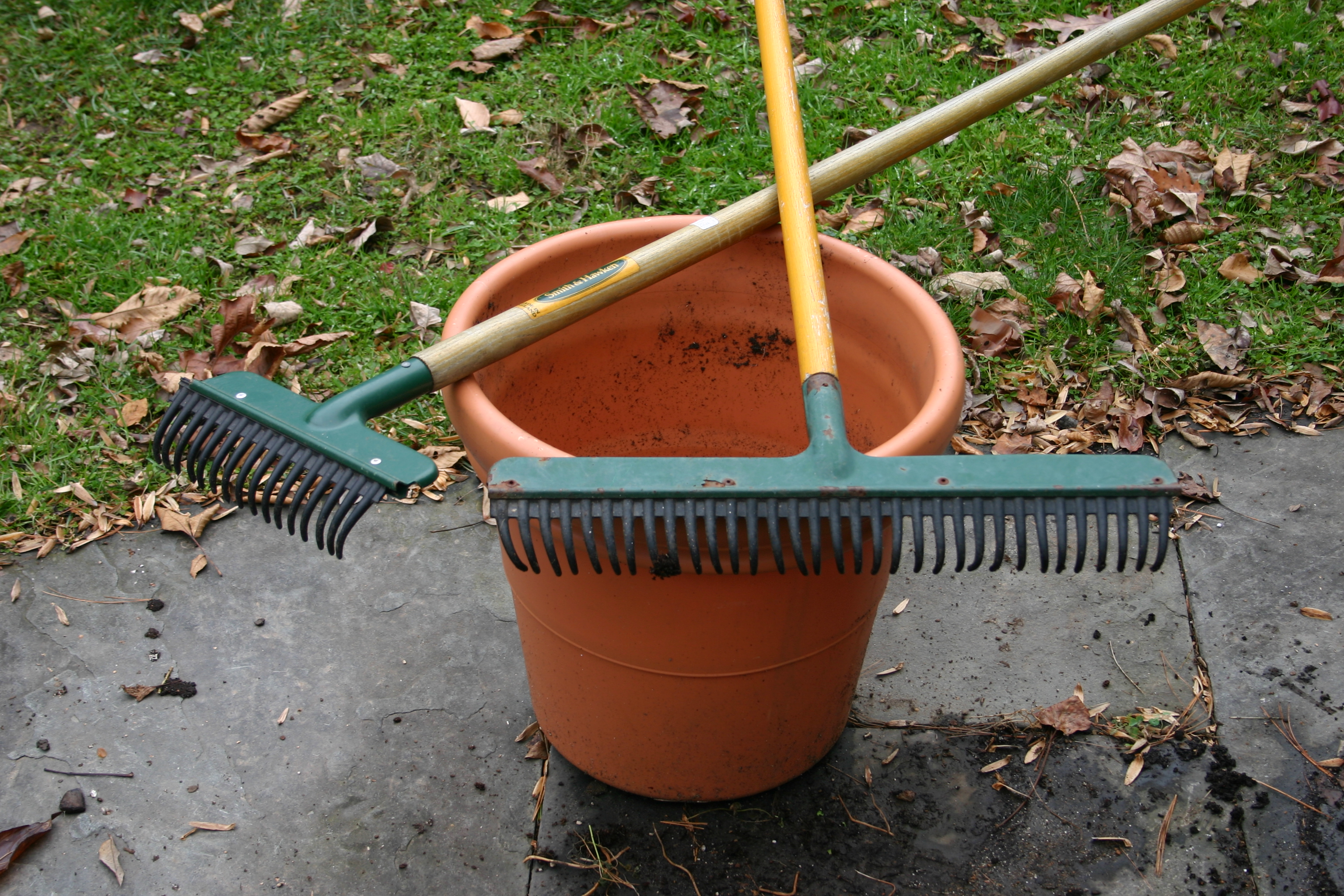 Two garden rakes on top of a plastic tub