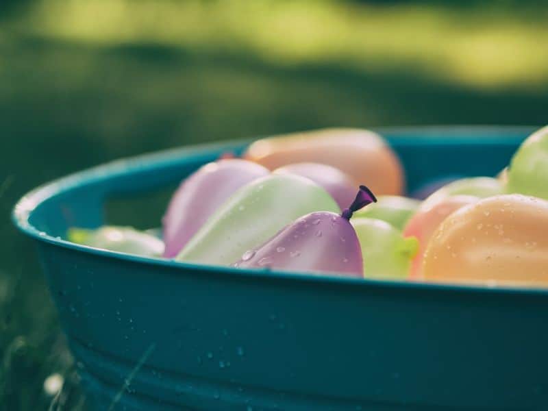 close up of multi-coloured water balloons in a bucket