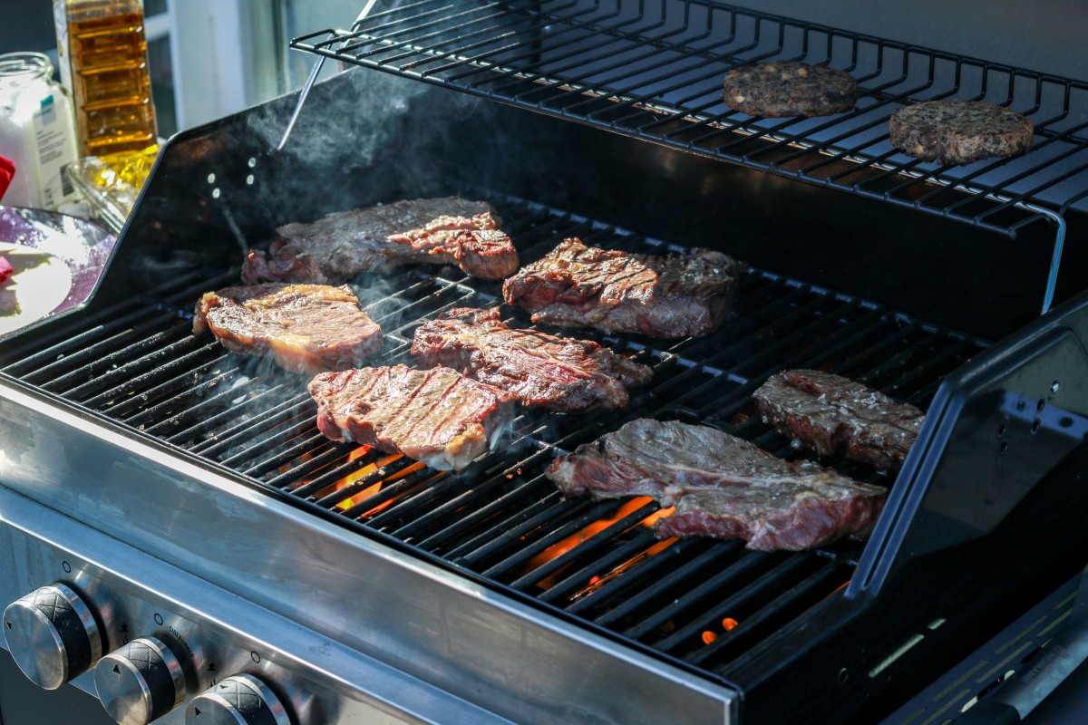 Burger patties being grilled on a gas BBQ