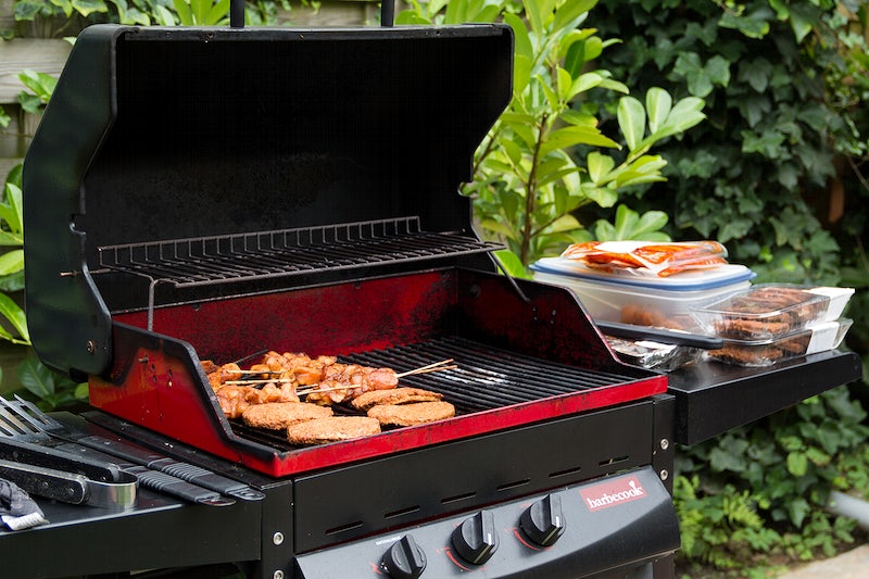 A black gas BBQ grill with an extendable side table