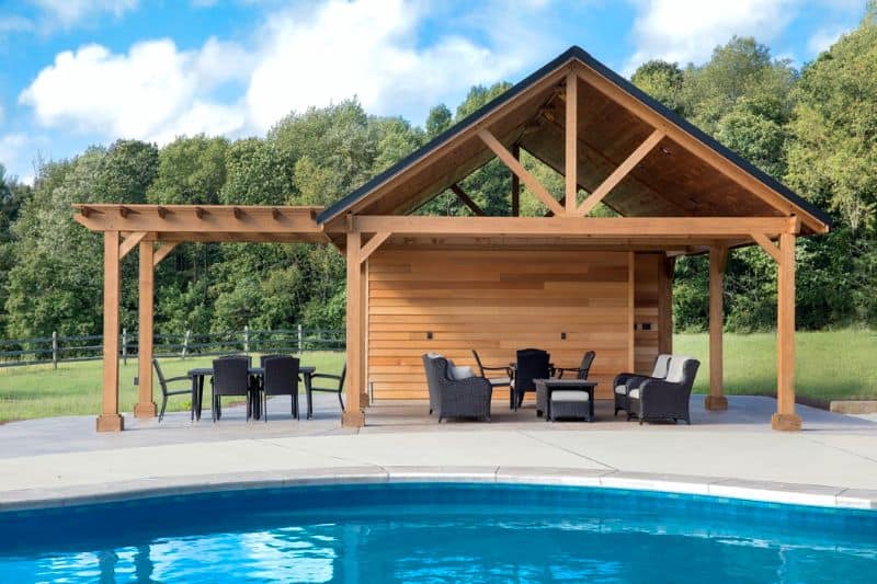 A backyard pool with rattan garden furniture in a pool shed