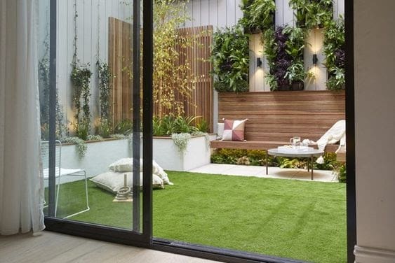 A small backyard with low-maintenance artificial grass and comfy garden cushions