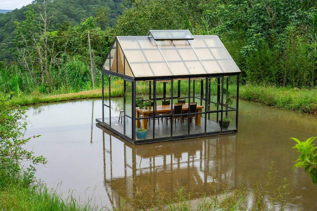 Small glass shed in the middle of a man-made garden lake