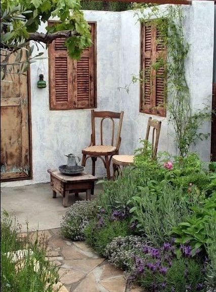 A french country garden with two small chairs and a couple of rustic shutters