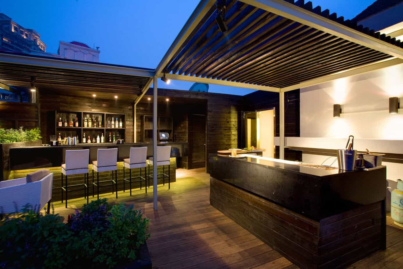 A secluded courtyard with cosy seating arrangement, pergola for shade, and a garden bar for entertainment