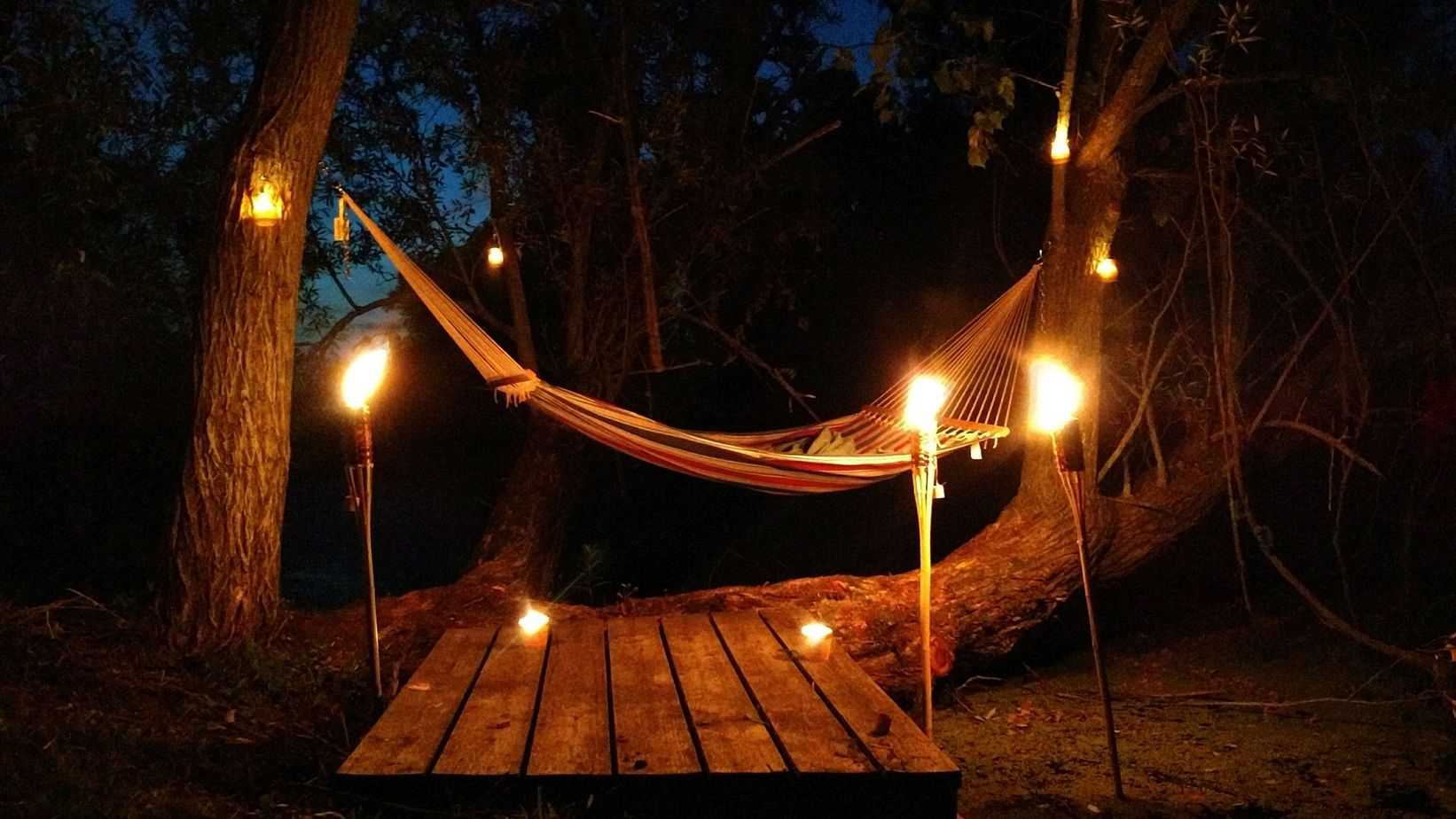 A hammock setup in the courtyard with lit tiki torches