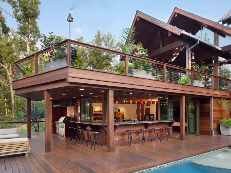A huge yard that features an L-shaped bar on wood decking and a pool
