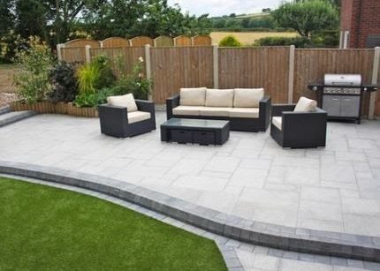 A bright sandstone paving outdoor lounge with grill and a rattan garden furniture set