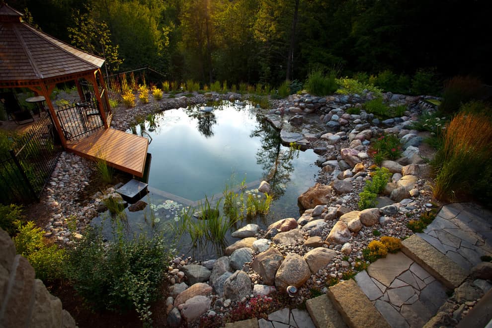 Circular garden pond surrounded with stones pavers