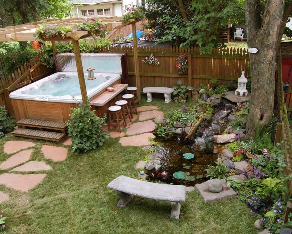 A corner garden setup with outdoor hot tub and small garden pond
