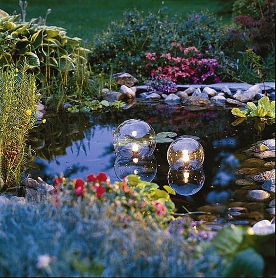 A garden pond with floating eclectic lighting