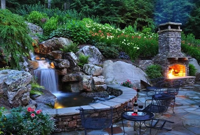 A waterfall, a brick oven on the side that can double as a fireplace, and some garden tables and chairs around the pond