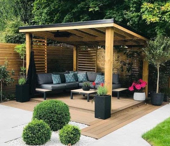 A modern decked area with a gazebo and wooden fence