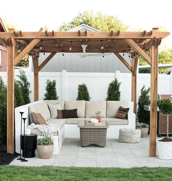 A garden pergola with a wooden roof and L-shaped corner sofa set