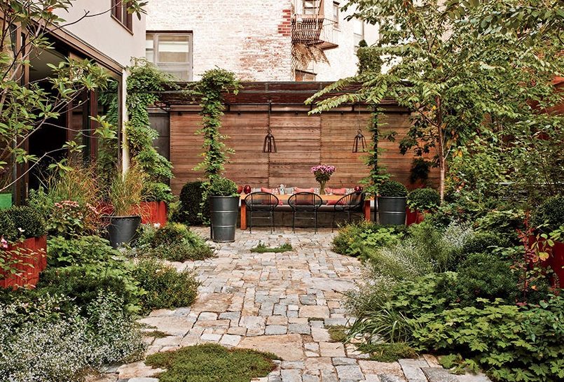 Tucked-away outdoor dining space set against at the back wall of a lush garden