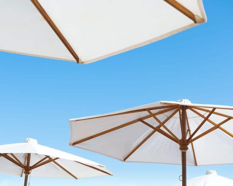 white parasol umbrellas on wooden frames against a blue sky