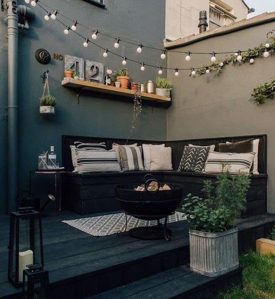 A comfy lounge on a deck, complete with lights and a fire pit