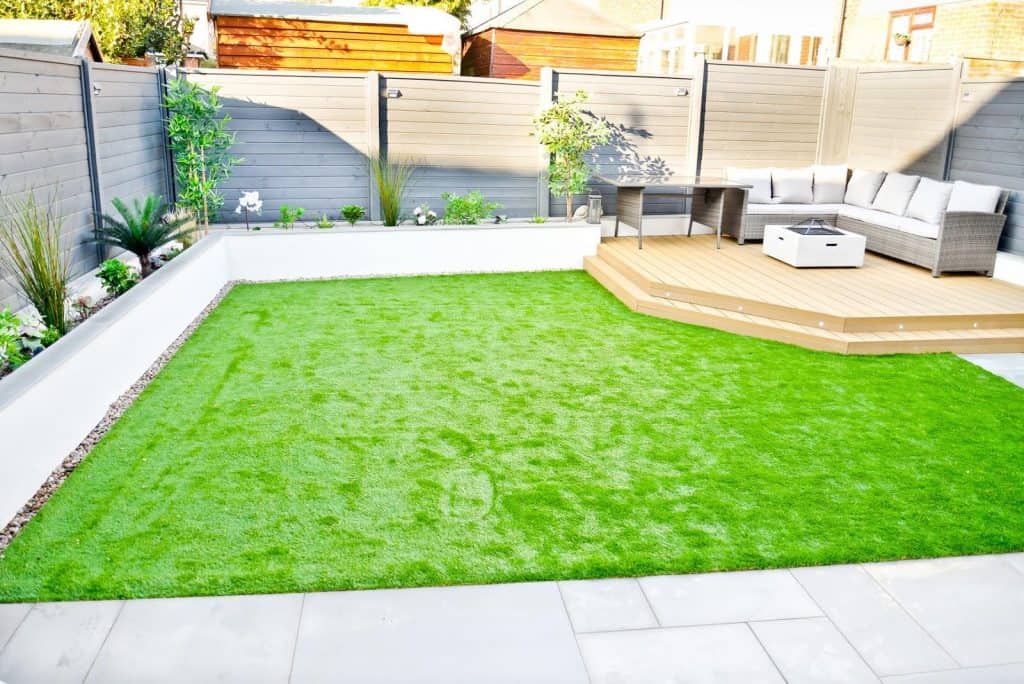 Open minimalist garden with large green lawn and raised decking