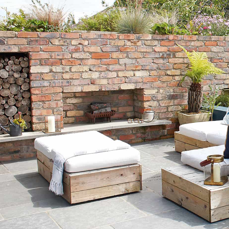 A garden with stone walls, outdoor seating area and a fireplace