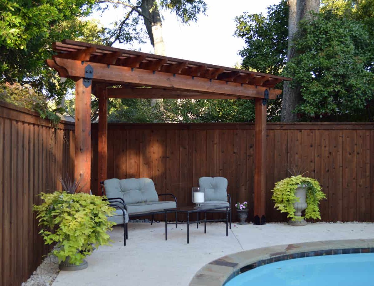 A pergola installed in the corner of the garden with a view of the swimming pool
