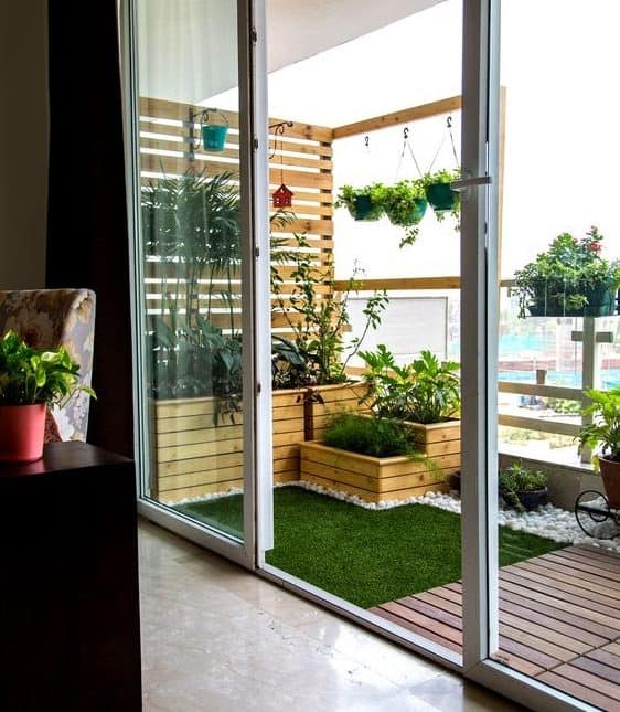 Artificial grass, decking and plenty of plants in a small balcony