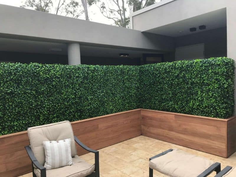 artificial hedges in boxing in a patio setting with chair