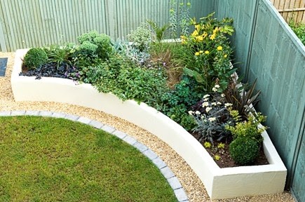 A corner garden bed with an attractive semi-circular raised garden bed and plant