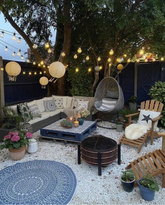 DIY outdoor lounge with comfy seating area, rug, and pretty lights