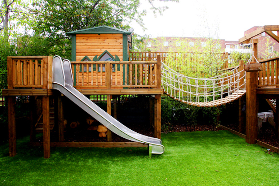 Big backyard playhouse with a rope bridge and slide