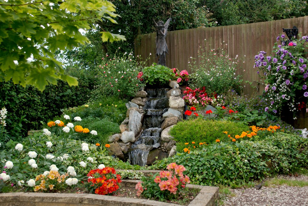 Small garden waterfall with surrounding flowers
