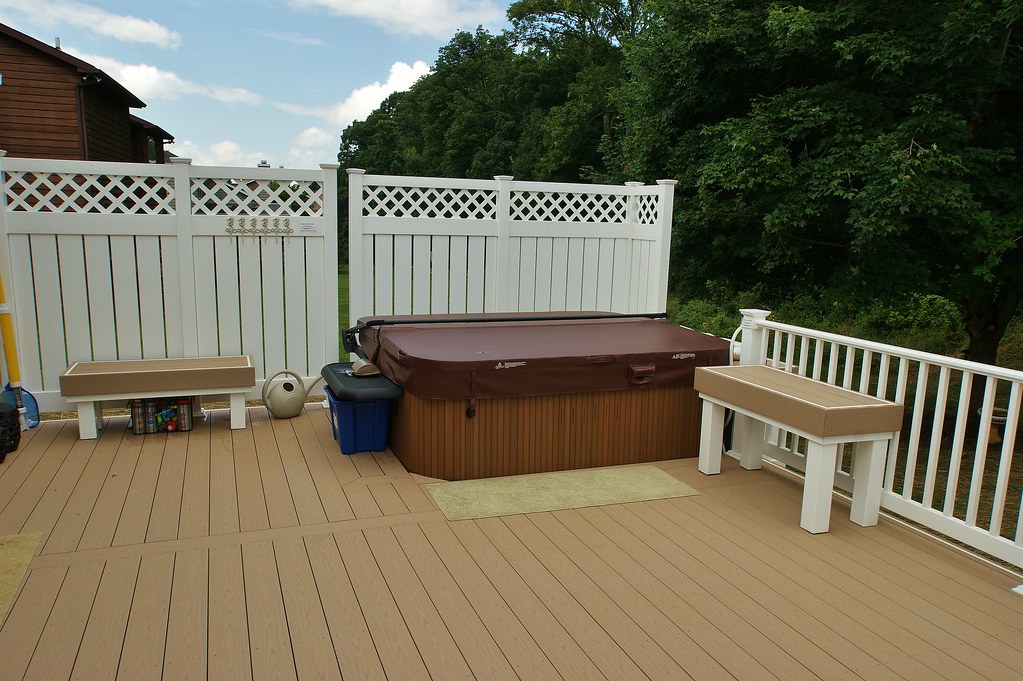 Outdoor hot tub on deck with a cover and surrounding benches