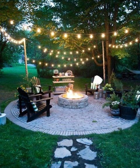 A circular seating area with hanging lights and a fire pit 