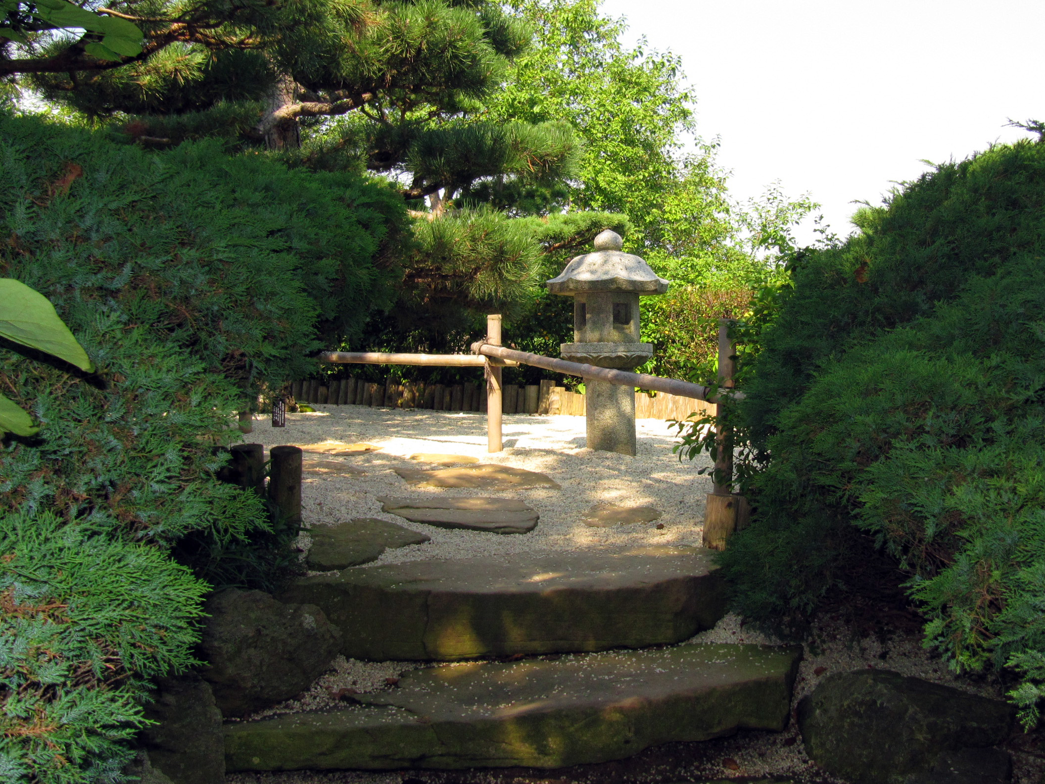 Japanese corner garden with bamboo water feature and rock lantern