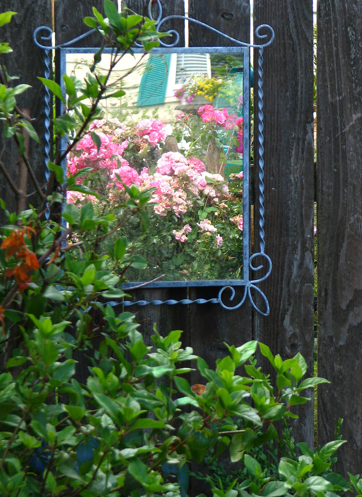 Blue mirror hung on a black garden fence