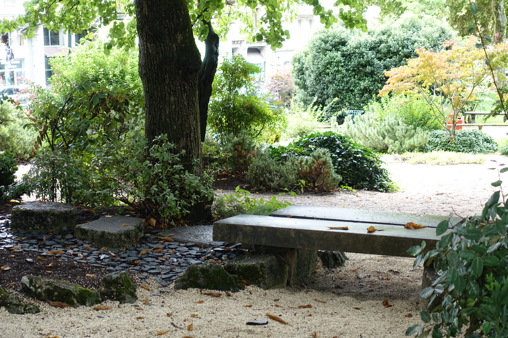 A bench in a Zen garden near a small pond.