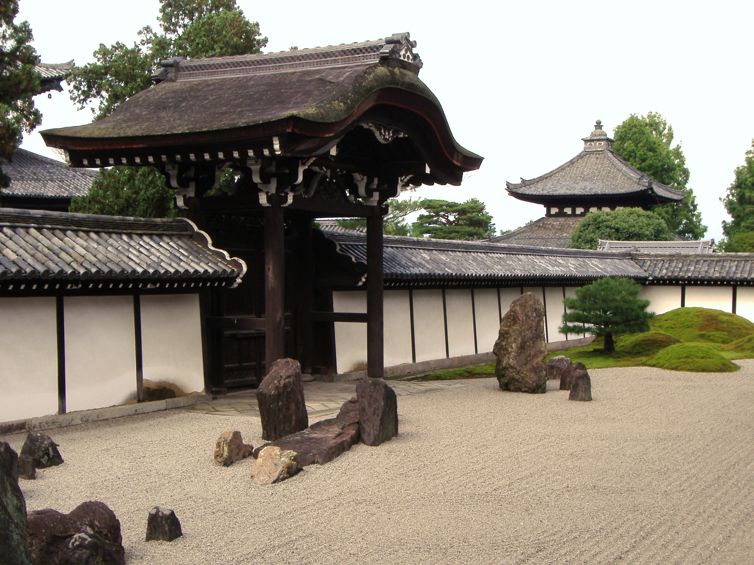 Modern Zen garden entrance with white sand and rock sculptures.