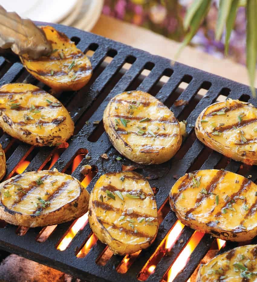 Sliced potatoes being grilled on a charcoal grill