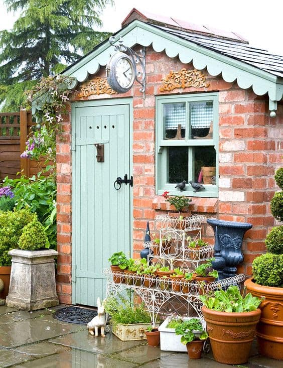 A small brick shed with potted plants at the front