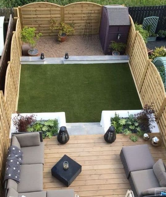 A stylish deck with comfy sofas and a shed in the corner of the garden