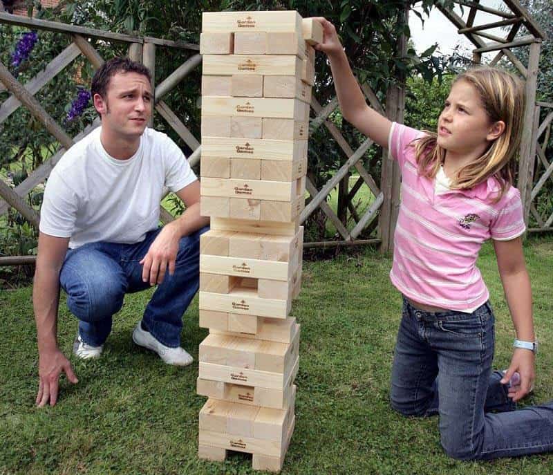 Father and daughter playing giant jenga outdoors